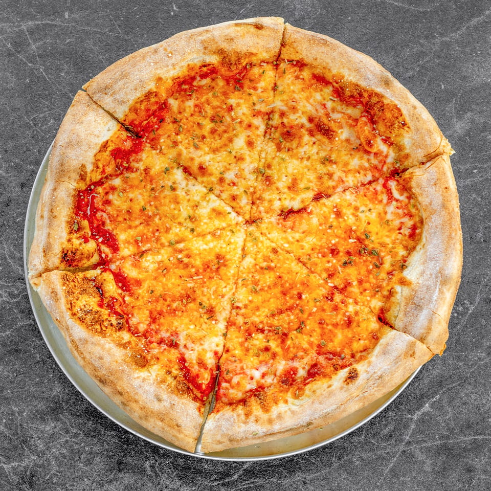 Whole cheese pizza topped with tomato sauce and herbs on a metal tray over a dark countertop.